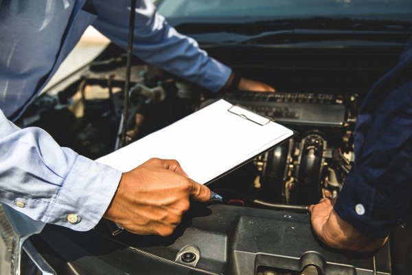 Mechanic with hand under the hood of a car